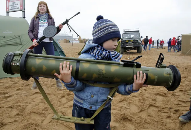 A boy holds a Russian anti-tank missile at a weapon exhibition during a military sports festival marking a state holiday, the Day of Russia, in St.Petersburg, Russia, Sunday, June 12, 2016. The holiday was established after the Soviet breakup to commemorate the emergence of an independent Russia. (Photo by Dmitri Lovetsky/AP Photo)