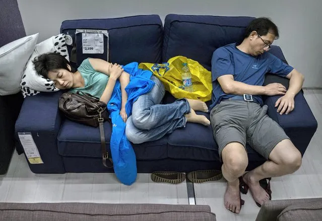 Chinese shoppers sleep on a sofa in the showroom of the IKEA store on July 6, 2014 in Beijing, China. Of the world's ten biggest Ikea stores, 8 of them are in China to cater to the country's growing middle class. The stores are designed with extra room displays given the tendency for customers to make a visit an all-day affair. Store management does not discourage shoppers from sleeping on Ikea furniture, even marking them with signs inviting customers to try them out. (Photo by Kevin Frayer/Getty Images)