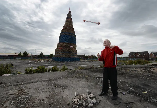 Curtis Walker throws his protestant band baton beside a Loyalist pyre on Lanark Way as final preparations are made for the 11th night bonfire, on July 11, 2014 in Belfast, Northern Ireland. The bonfire at Lanark Way, the tallest in Northern Ireland, stands at over 200ft high and is made of pallets gathered by Loyalists to mark the beginning of the annual 12th of July Orange parade. (Photo by Charles McQuillan/Getty Images)