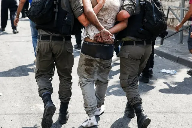 Israeli security forces detain a Palestinian protester during clashes following prayers outside Jerusalem's Old City on July 21, 2017, after Israeli police barred men under 50 from entering the Old City for Friday Muslim prayers as tensions rose and protests erupted over new security measures at the highly sensitive Al-Aqsa mosque compound. The ban came after Israeli ministers decided not to order the removal of metal detectors erected at entrances to the Al-Aqsa mosque compound, known to Jews as the Temple Mount, following an attack nearby a week ago that killed two policemen. (Photo by Ahmad Gharabli/AFP Photo)