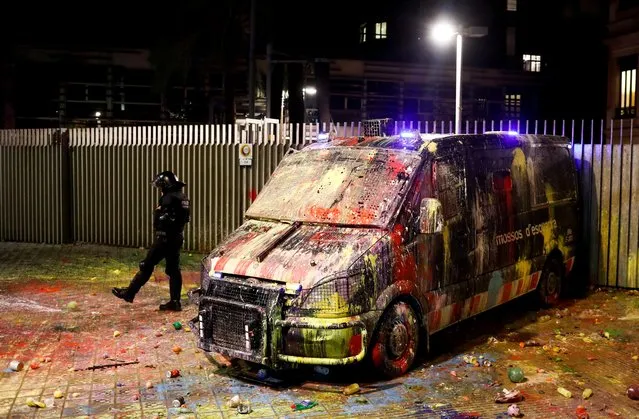 A police officer kicks a balloon next to a van that was covered with paint during a protest outside the Spanish government delegation offices in Barcelona, Spain, October 21, 2019. (Photo by Jon Nazca/Reuters)