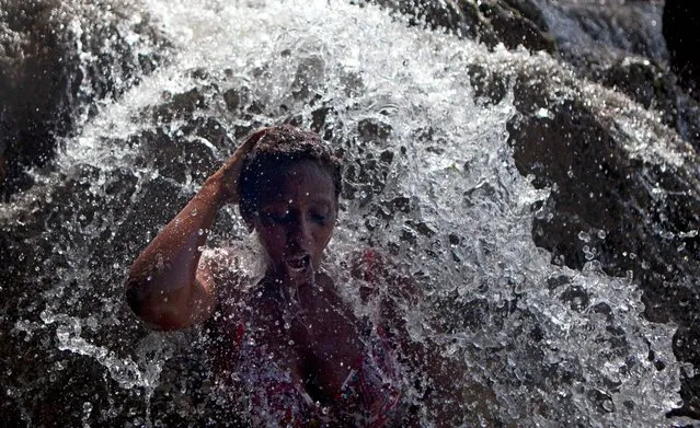 A voodoo pilgrim bathes in a waterfall believed to have purifying powers during the annual celebration in Saut d' Eau, Haiti, Wednesday, July 16, 2014. An annual pilgrimage is made in honor of Haiti's most celebrated patron saint, Our Lady of Mount Carmel, who is supposed to have appeared on a palm tree in 1847 in the Palm Grove in Saut d'Eau and was integrated into Haiti's voodoo culture as the goddess of love. (Photo by Dieu Nalio Chery/AP Photo)