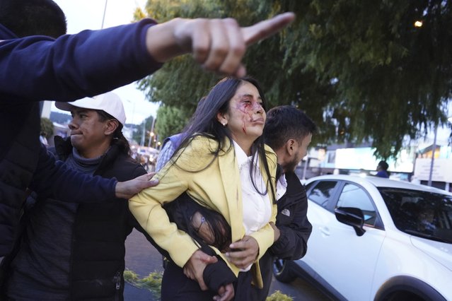 A bloodied woman is carried away after presidential candidate Fernando Villavicencio was shot to death while at a campaign rally outside a school in Quito, Ecuador, Wednesday, August 9, 2023. (Photo by API via AP Photo)