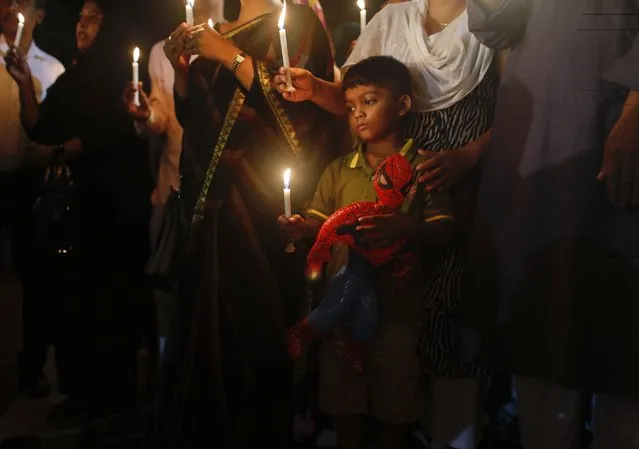 A Bangladeshi boy holds a Spiderman toy in one hand and a lighted candle in the other as he joins elders in paying tribute to those killed in the attack at the Holey Artisan Bakery in Dhaka, Bangladesh, Sunday, July 3, 2016. (Photo by AP Photo)