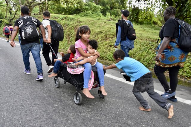 Children ride in a stroller along the Huixtla highway in the state of Chiapas, Mexico, October 22, 2024, as part of a group of migrants hoping to reach the country's northern border and ultimately the United States. (Photo by Edgar H. Clemente/AP Photo)