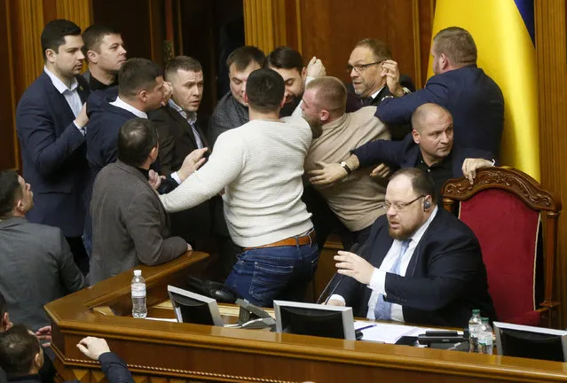 Ukrainian lawmakers scuffle around the rostrum during a parliament session in Kyiv, Ukraine, Thursday, February 6, 2020. The Ukrainian parliament to considering the law to lift the ban on sales of farmland. (Photo by Efrem Lukatsky/AP Photo)