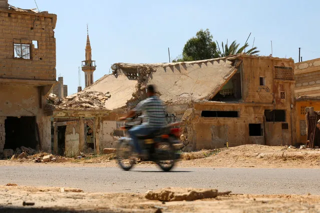 A man rides a motorbike past damaged buildings along a street in the rebel-held town of Dael, in Deraa Governorate, Syria July 7, 2016. (Photo by Alaa Al-Faqir/Reuters)