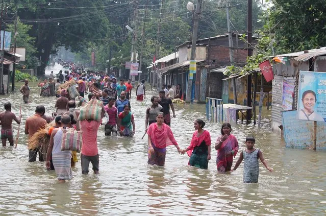 Indian residents wade through flood waters in Balurghat in West Bengal on August 17, 2017. At least 221 people have died and more than 1.5 million have been displaced by monsoon flooding across India, Nepal and Bangladesh, officials said August 15, as rescuers scoured submerged villages for the missing. (Photo by AFP Photo/Stringer)