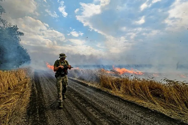 A Ukrainian serviceman walks on a burning wheat field near a frontline on a border between Zaporizhzhia and Donetsk regions, as Russia’s attack on Ukraine continues, Ukraine on July 17, 2022. (Photo by Dmytro Smolienko/Reuters)