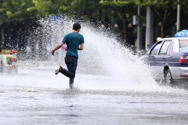A man rans on a flooded street while a taxi splashes water as it drives past after a heavy rainfall hit Shanghai, China, August 24, 2015. (Photo by Aly Song/Reuters)