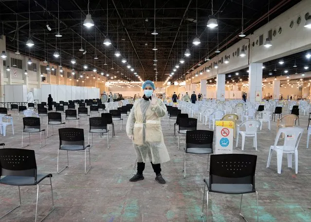 A volunteer, that directs visitors at a coronavirus testing centre, gestures at the Kuwait International Fairgrounds in Mishref, Kuwait on March 18, 2020. (Photo by Stephanie McGehee/Reuters)