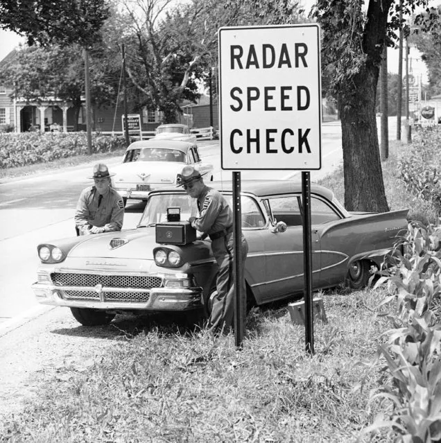 Corp. Clayton W. Hamberger, right, and Trooper Eric A. Bornemann of the Pennsylvania State police pose with a radar machine on the fender of their car underneath a newly erected radar speed check sign on route 30 near York, Pennsylvania on June 30, 1960. A motorist can not be arrested on the basis of a radar check but State Police are using the electronic device to single out speeding motorists for warnings. (Photo by Paul Vathis/AP Photo)