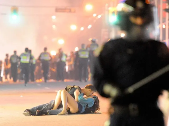 Riot police walk in the street as a couple kiss on June 15, 2011 in Vancouver, Canada. Vancouver broke out in riots after their hockey team the Vancouver Canucks lost in Game Seven of the Stanley Cup Finals. (Photo by Rich Lam/Getty Images)