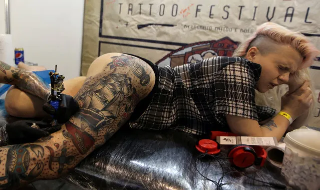 A client reacts as she is tattooed during the Tattoo Week SP 2016 in Sao Paulo, Brazil, July 23, 2016. (Photo by Paulo Whitaker/Reuters)