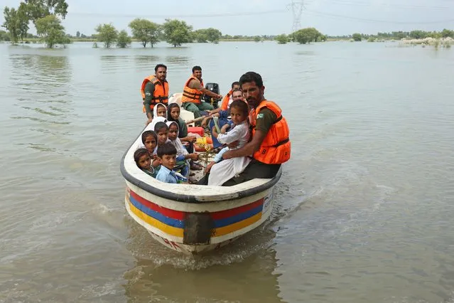 Rescue workers use a boat to drop children back home after school in a flood hit area following heavy monsoon rains in Dera Ghazi Khan district in Punjab province on August 29, 2022. The death toll from monsoon flooding in Pakistan since June has reached 1,136, according to figures released on August 29 by the country's National Disaster Management Authority. (Photo by Shahid Saeed Mirza/AFP Photo)
