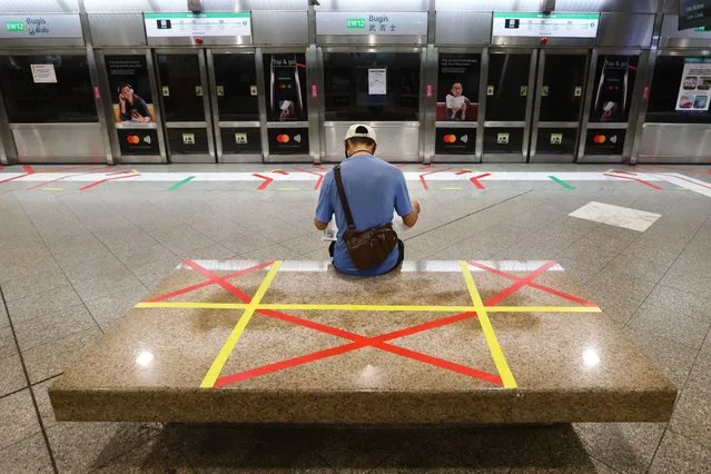 A man reading a newspaper sits on an unmarked safety distancing marker at a train station on April 21, 2020 in Singapore. Singapore recorded a daily high of 1426 new coronavirus (COVID-19) cases on April 20, bringing the country's total to 8014.(Photo by Suhaimi Abdullah/Getty Images)
