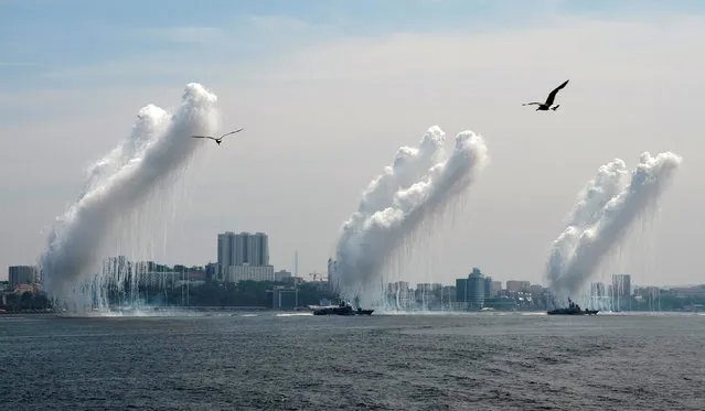 Seagulls fly as warships fire anti-missile ordnance during the Navy Day celebration in the far eastern port of Vladivostok, Russia, July 31, 2016. (Photo by Yuri Maltsev/Reuters)
