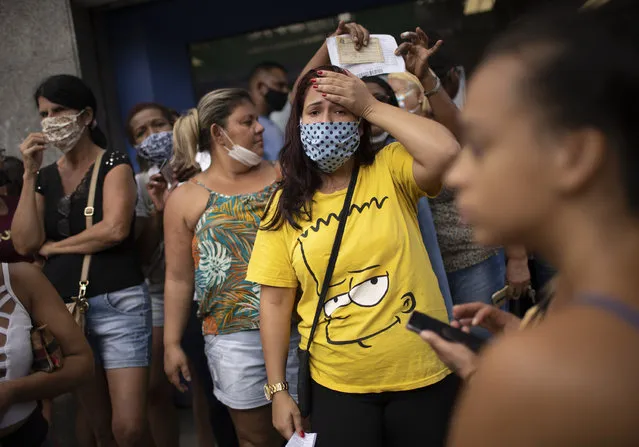 People out of work wait outside a government-run bank having technical problems to distribute their aid money amid the new coronavirus pandemic's affect on the economy in Rio de Janeiro, Brazil, Tuesday, April 28, 2020. (Photo by Silvia Izquierdo/AP Photo)