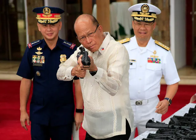 Philippine Defense Secretary Delfin Lorenzana (C) aims an automatic rifle during the turnover ceremony of China's urgent military assistance to the Philippines at the military camp in Camp Aguinaldo in Quezon city, metro Manila, Philippines October 5, 2017. (Photo by Romeo Ranoco/Reuters)