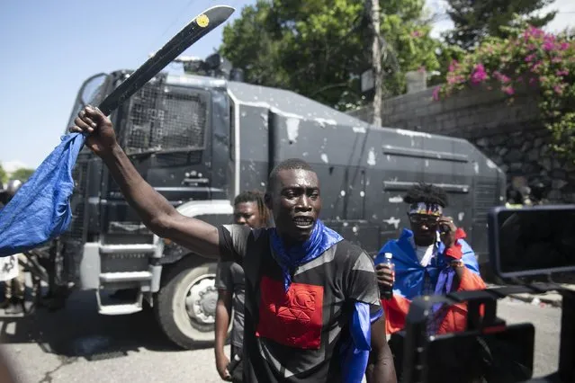 A man holds up a machete during a protest to demand that Haitian Prime Minister Ariel Henry step down and a call for a better quality of life, in Port-au-Prince, Haiti, Wednesday, September 7, 2022. (Photo by Odelyn Joseph/AP Photo)