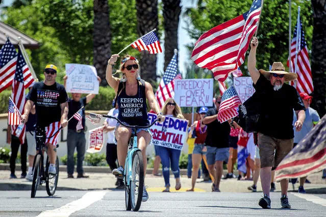 Protesters wave flags during a demonstration against California’s stay-at-home orders in Rancho Cucamonga, US on May 3, 2020. (Photo by Watchara Phomicinda/AP Photo)