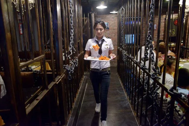 This picture taken on September 9, 2014 shows a waiter carrying food to customers at a prison themed restaurant in Tianjin. (Photo by Wang Zhao/AFP Photo)