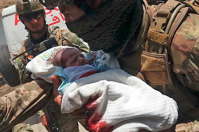 An Afghan security personnel carries a newborn baby from a hospital, at the site of an attack in Kabul on May 12, 2020. Gunmen stormed a hospital on May 12 in an ongoing attack in the Afghan capital Kabul, a government official and a fleeing doctor said. (Photo by AFP Photo/Stringer)