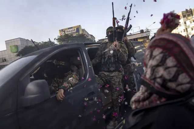 A woman showers Palestinian fighters from Islamic Jihad with flower petals as they take part in an anti-Israel rally in Rafah, south of Gaza City, Wednesday, August 24, 2022. (Photo by Fatima Shbair/AP Photo)