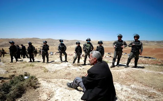 A Palestinian man sits in front of Israeli troops during a protest against Israeli machineries operating near Ramallah in the Israeli-occupied West Bank on May 26, 2020. (Photo by Mohamad Torokman/Reuters)