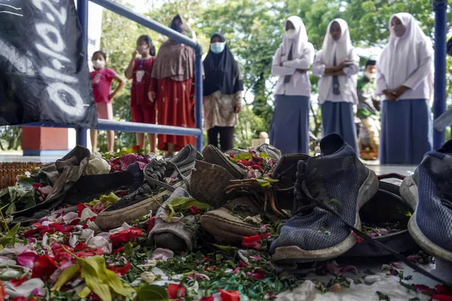 Victims' shoes left near one of the gates of Kanjuruhan Stadium, the site of Saturday's soccer stampede, are seen sprinkled with flowers in Malang, East Java, Indonesia, Tuesday, October 4, 2022. Police firing tear gas inside the stadium on Saturday in an attempt to stop violence after an Indonesian soccer match triggered a disastrous crush of fans making a panicked, chaotic run for the exits, leaving at more than 100 people dead, most of them trampled upon or suffocated. (Photo by Dicky Bisinglasi/AP Photo)