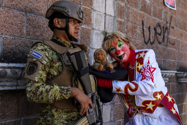 A clown poses for a picture next to a soldier during the National Day of the Salvadoran Clown, celebrated every first Wednesday of December, in San Salvador on December 6, 2023. (Photo by Camilo Freedman/AFP Photo)