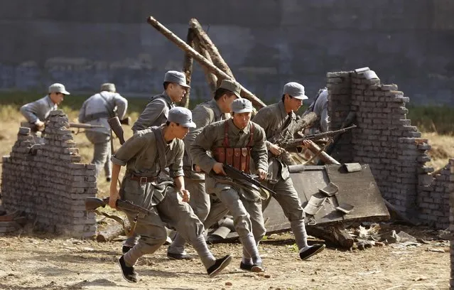 Performers and tourists dressed in military costumes hold toy guns during a performance of a battle scene between China and Japan, at a film city in Shenyang, Liaoning province September 24, 2014. The live performance, which involved 60 detonations, welcomed tourists at the site to participate, local media reported. (Photo by Reuters/Stringer)