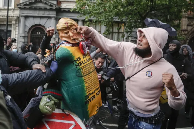 A demonstrator punches a puppet depicting US President Donald Trump during a Black Lives Matter march in London, Saturday, June 6, 2020, as people protest against the killing of George Floyd by police officers in Minneapolis, USA. Floyd, a black man, died after he was restrained by Minneapolis police while in custody on May 25 in Minnesota. (Photo by Frank Augstein/AP Photo)