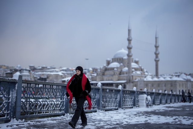 Backdropped by the New mosque, a woman walks on the Galata Bridge after a snowfall in Istanbul, Turkey, Friday, February 21, 2025. (Photo by Emrah Gurel/AP Photo)
