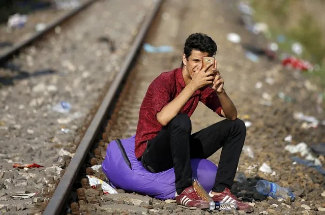 A migrant uses his mobile device as he rests on railways after crossing into the country from Serbia at the border near Roszke, Hungary September 13, 2015. (Photo by Dado Ruvic/Reuters)