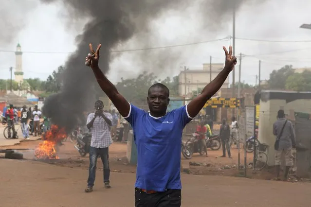A protester gestures in front of a burning roadblock in Ouagadougou, Burkina Faso, September 18, 2015. Security forces in the capital of Burkina Faso fired in the air on Friday to disperse demonstrators who burned tyres and blocked neighborhood streets to protest at a military coup this week that derailed a democratic transition. (Photo by Joe Penney/Reuters)