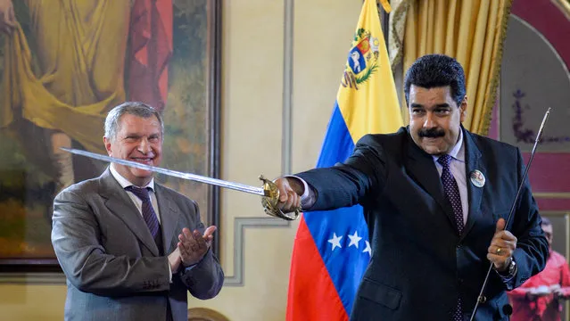 Venezuelan President Nicolas Maduro (R) holds a sword, given as gift by Russian oil company Rosneft's CEO, Igor Sechin, during the signing of agreements at Miraflores presidential Palace in Caracas on July 28, 2016. (Photo by Federico Parra/AFP Photo)