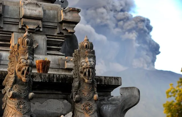 Mount Agung's eruption is seen next to a Balinese temple at Kubu sub-district in Karangasem Regency on Indonesia's resort island of Bali on November 26, 2017. (Photo by Sonny Tumbelaka/AFP Photo)