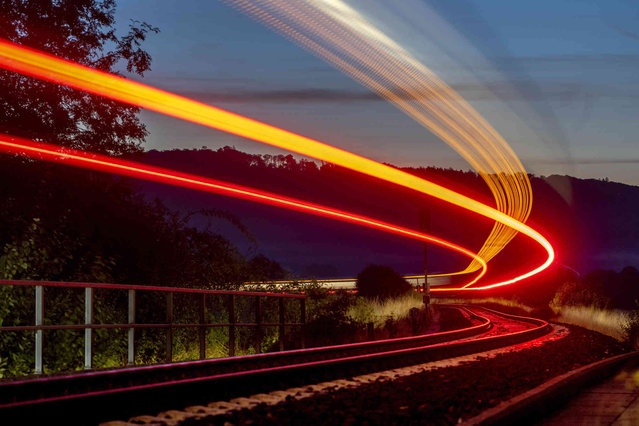 Long time exposure photo shows a regional train approaching the station of Wehrheim near Frankfurt, Germany, early Friday, September 23, 2022. (Photo by Michael Probst/AP Photo)