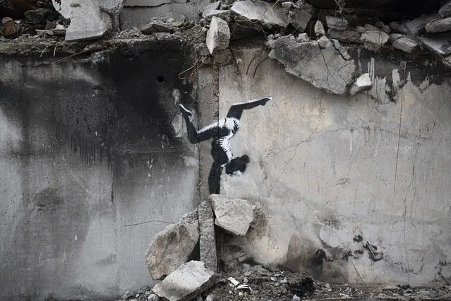 An artwork by British street artist Banksy is seen on a destroyed by fightings building in Borodyanka, Kyiv region, Ukraine, Sunday, November 13, 2022. (Photo by Andrew Kravchenko/AP Photo)