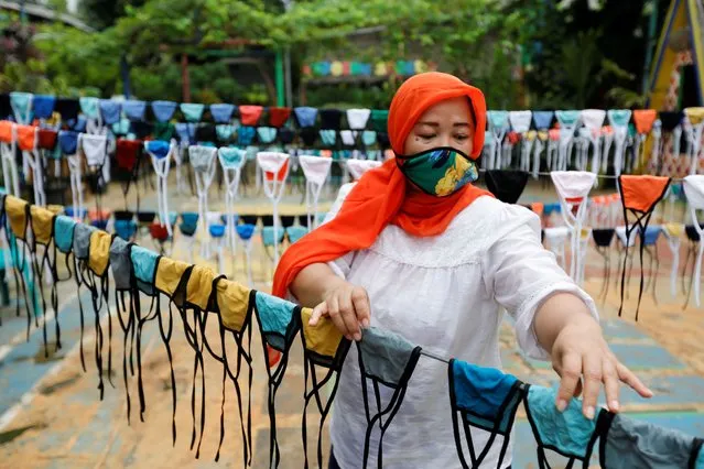 A woman puts cloth face masks on a string to dry before distributing it for free around the neighbourhood, amid the spread of coronavirus disease (COVID-19) outbreak, in Tangerang, on the outskirts of Jakarta, Indonesia, April 9, 2020. (Photo by Willy Kurniawan/Reuters)