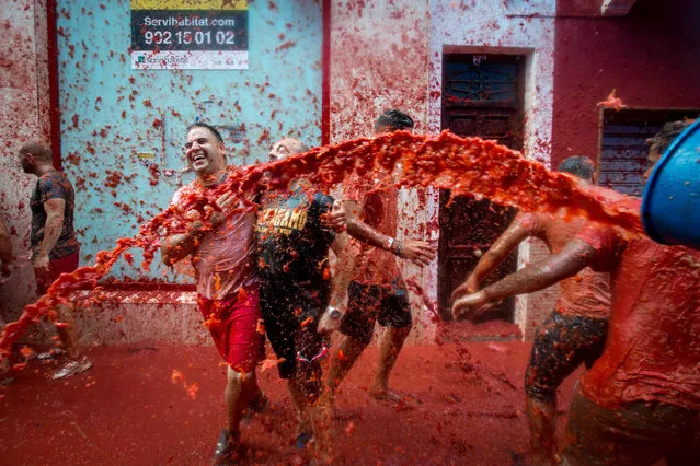 Revellers covered in tomato pulp participate in the annual “Tomatina” festivities in the village of Bunol, near Valencia on August 31, 2016. (Photo by Biel Alino/AFP Photo)