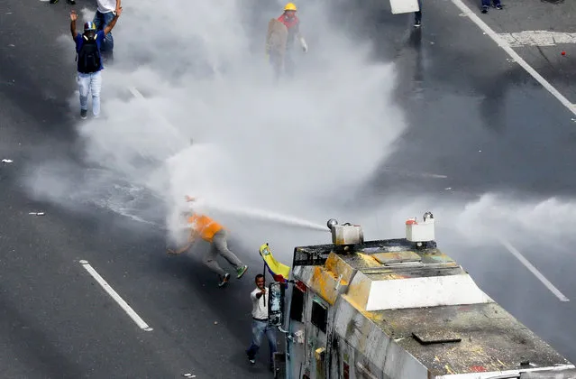 Opposition lawmaker Carlos Paparoni is hit by jets of water during riots at a march to the state ombudsman's office in Caracas, Venezuela, May 29, 2017. A group of young Venezuelan lawmakers has risen to prominence on the violent front line of anti-government marches that have shaken the South American country for three months, bringing 75 deaths. On the streets daily leading demonstrators, pushing at security barricades and sometimes picking up teargas canisters to hurl back at police and soldiers, the energetic National Assembly members are heroes to many opposition supporters. Carlos Garcia Rawlins: “I remember clearly how instants after I spotted Paparoni standing in front of “The Whale”, the common name of the water cannon armoured cars, he was flying through the air due to the unstoppable power of the water, as if he was a feather. Fellow protesters had to drag him out of the place, because from where I was, he seemed to have been unconscious”. (Photo by Carlos Garcia Rawlins/Reuters)