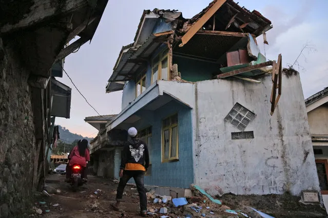 A man walks past a house damaged by an earthquake in Cianjur, West Java, Indonesia, Monday, November 21, 2022. The strong, shallow earthquake toppled buildings and collapsed walls on Indonesia's densely populated main island of Java on Monday, killing a number of people and injuring hundreds as people rushed into the streets, some covered in blood and white debris. (Photo by Rangga Firmansyah/AP Photo)