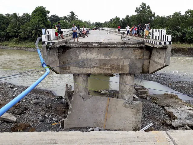 People gather on a bridge which was damaged by the onslaught of the flooding brought about by tropical storm Tembin, Sunday, December 24, 2017 in Zamboanga Del Sur in southern Philippines. Tropical Storm Tembin unleashed flash floods that swept away people and houses and set off landslides in the southern Philippines. (Photo by Daisy Barimbao/AP Photo)