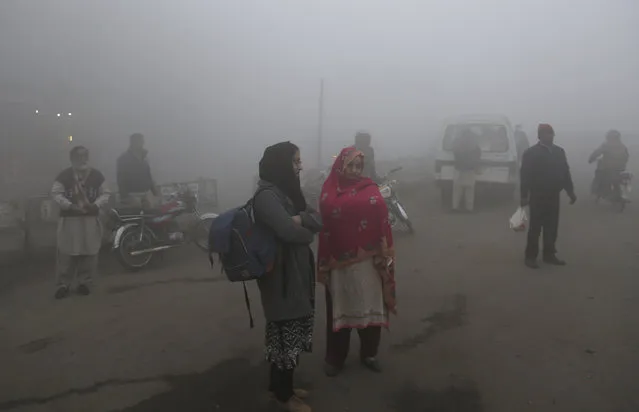 People wait for transport as heavy fog envelope the areas of Lahore, Pakistan, Thursday, December 28, 2017. Various cities in eastern and central Pakistan continue to experience heavy fog, disrupting air and road transportation. (Photo by K.M. Chaudary/AP Photo)
