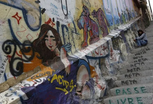 A woman sit on stairs beside a grafitti-covered home in downtown Valparaiso city, Chile June 27, 2015. (Photo by Henry Romero/Reuters)