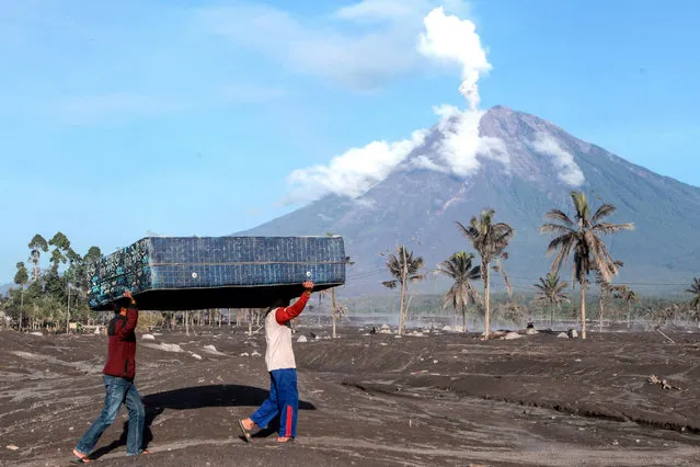 People move their personal belongings to safe place after the eruption of Mount Semeru at Sumberwuluh village in Lumajang, East Java, Indonesia, December 6, 2022. Semeru volcano on Indonesia's Java island erupted on Sunday, spewing a 1.5-km high ash column, authorities said. (Photo by Bayu Novanta/Xinhua/Alamy Live News)