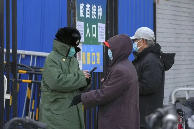 A couple seek information about the vaccine with a security guard at an entrance gate to a vaccination site in Beijing, Tuesday, December 20, 2022. China continues to adapt to an easing of strict virus containment regulations. (Photo by Andy Wong/AP Photo)