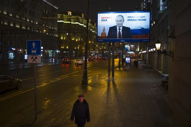 A man walks past a Russian President Vladimir Putin's campaign poster reading “Strong president – strong Russia” and “Presidential elections will be held in Russia in March 18” in Moscow, Russia, Monday, January 15, 2018. Putin is set to easily win another six-year term in the vote. (Photo by Alexander Zemlianichenko/AP Photo)